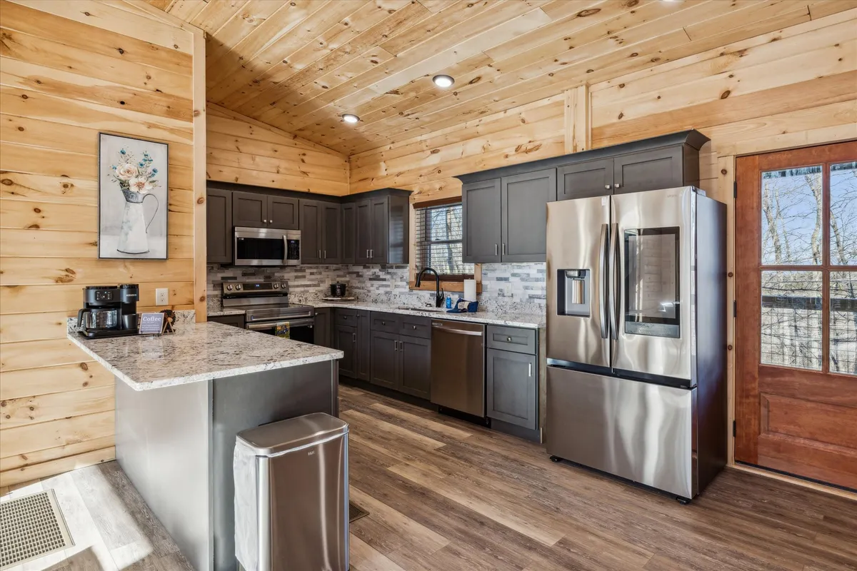 A modern kitchen featuring granite countertops, stainless steel appliances, and wooden cabinetry. Decorative wall art and thoughtful lighting add to the room's warmth, making it an inviting spot for cooking and entertaining guests.