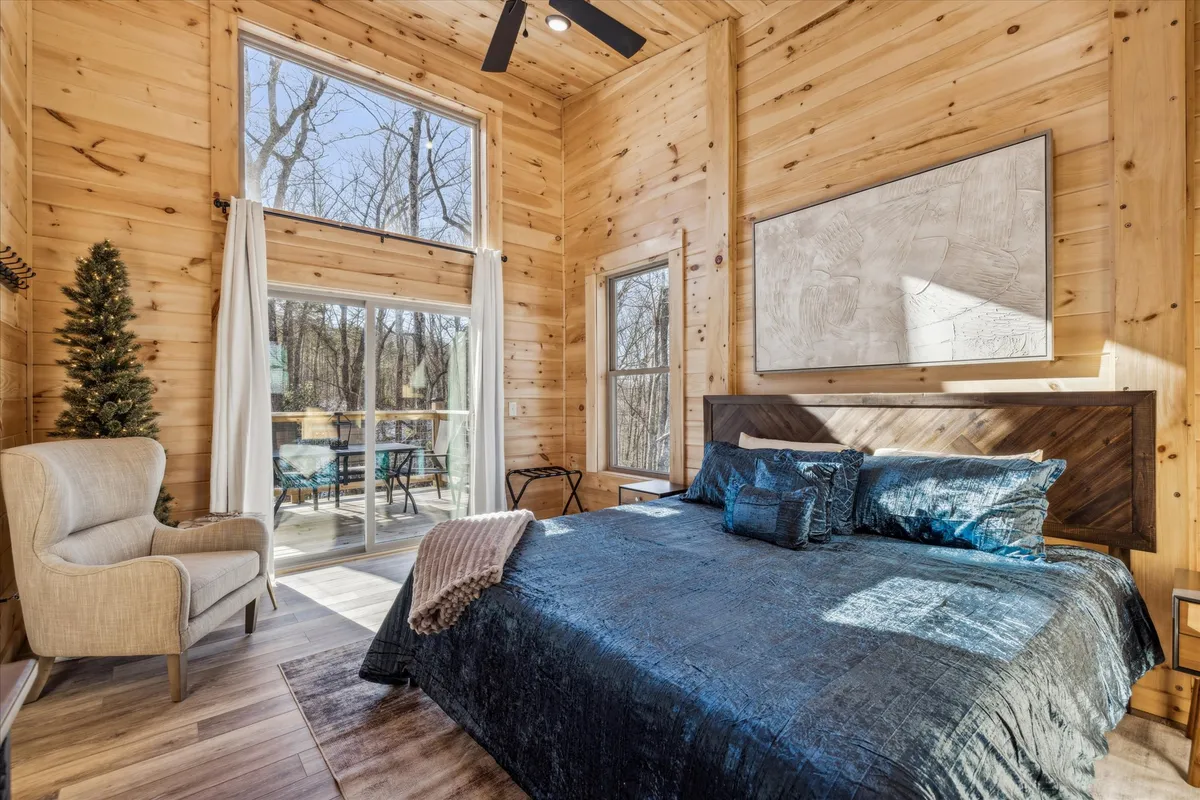 A tranquil bedroom with a luxurious bed dressed in blue bedding, large windows streaming in natural light, and a stylish armchair positioned for peaceful moments. The room exudes comfort and relaxation, perfect for unwinding after a day of adventure.