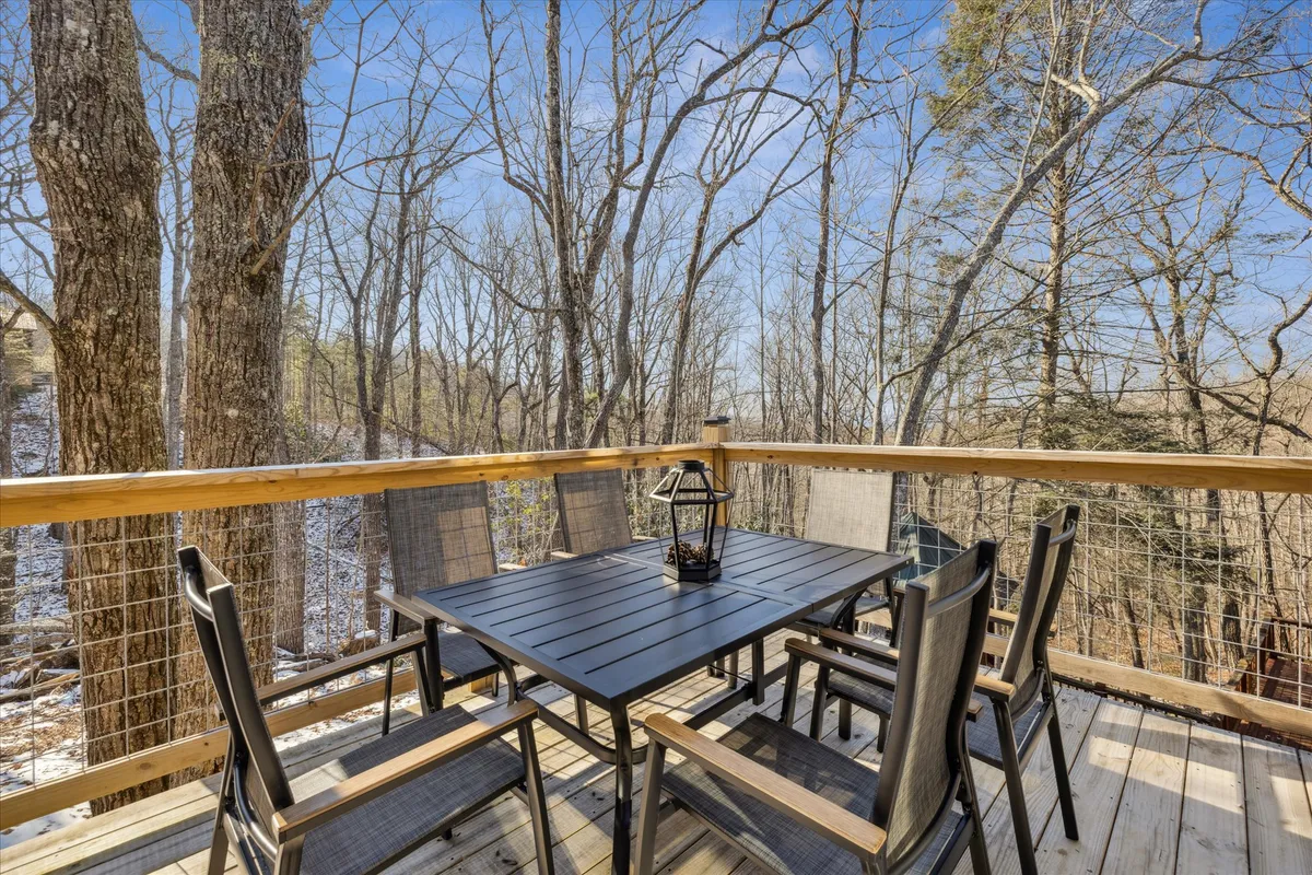 An outdoor dining area set amid trees, featuring a dining table, chairs, and a lantern. The tranquil scene suggests opportunities for sunset dinners, morning coffee, or simply relaxing while immersed in nature.